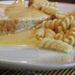 Preparazione della besciamella senza grumi, con latte caldo versato tutto in una volta in una pentola.