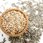 Semi di girasole su sfondo bianco, ricchi di vitamina E, simbolo di bellezza e anti-age naturale.