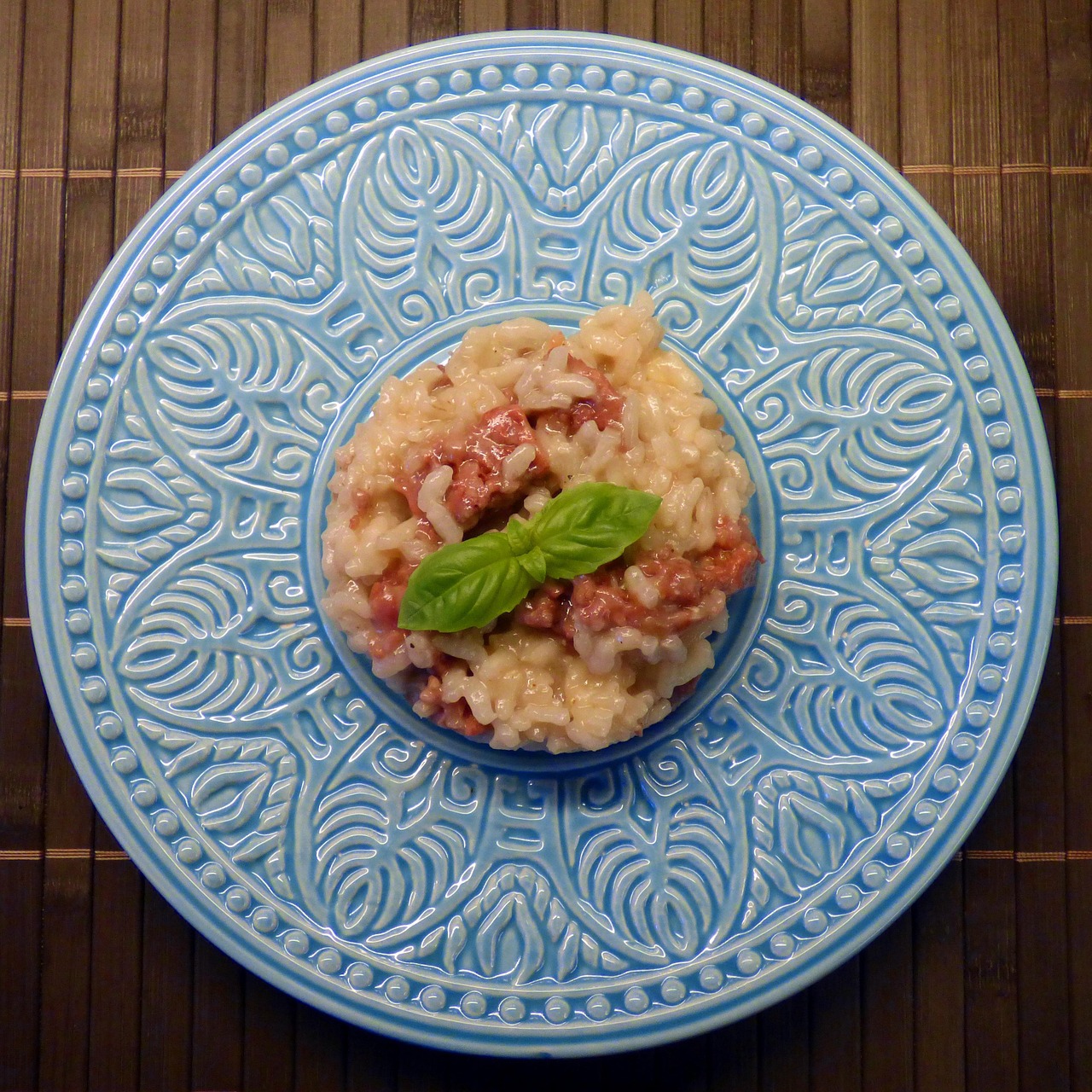Risotto cremoso in una ciotola, guarnito con prezzemolo fresco e burro freddo da freezer accanto.