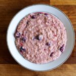 Porridge d'avena pronto per colazione, servito in una ciotola con frutta fresca e noci.