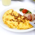 Frittata soffice e leggera su un piatto, con ingredienti freschi e colorati intorno.